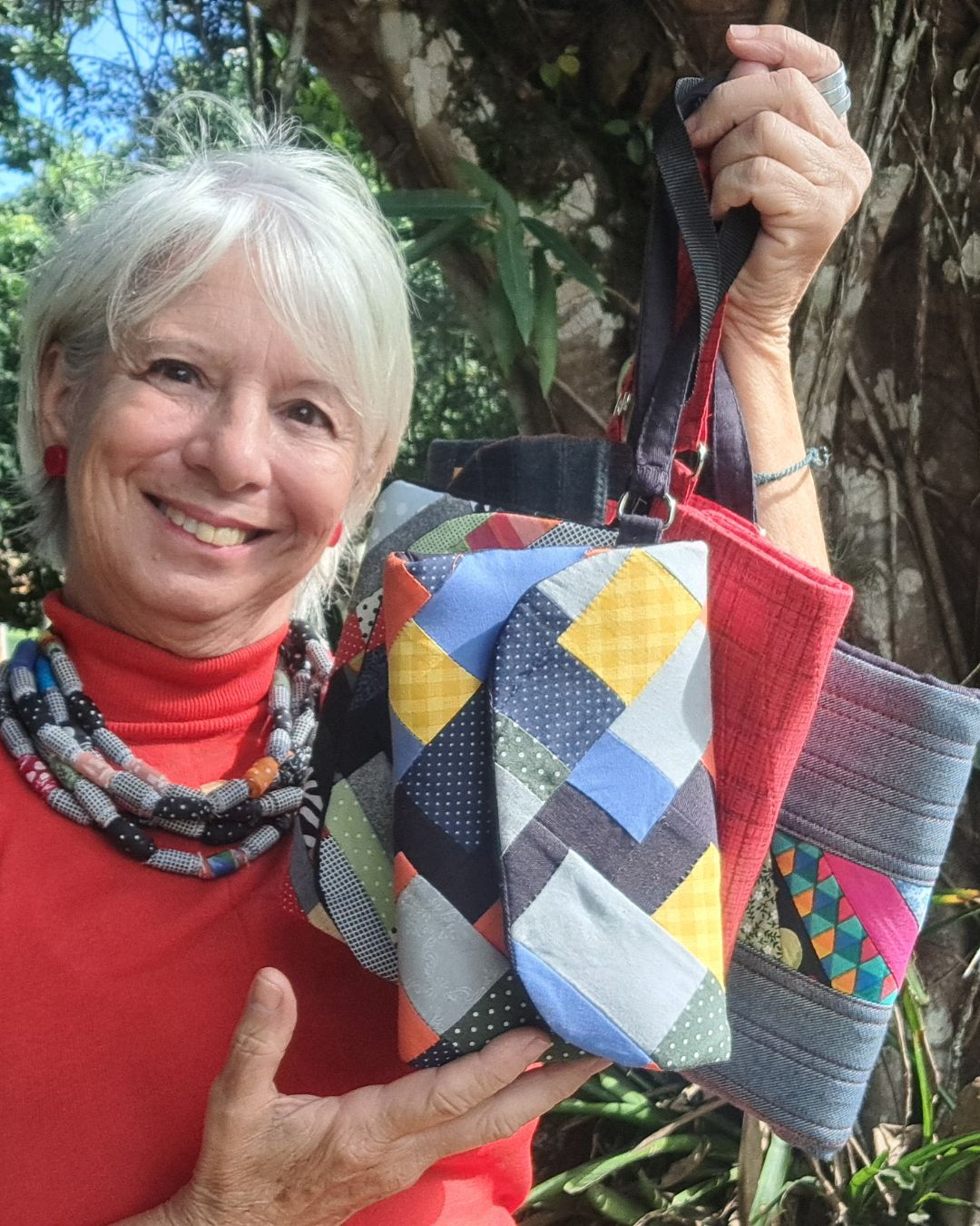 Professora Maria Antonia segurando carteiras de patchwork